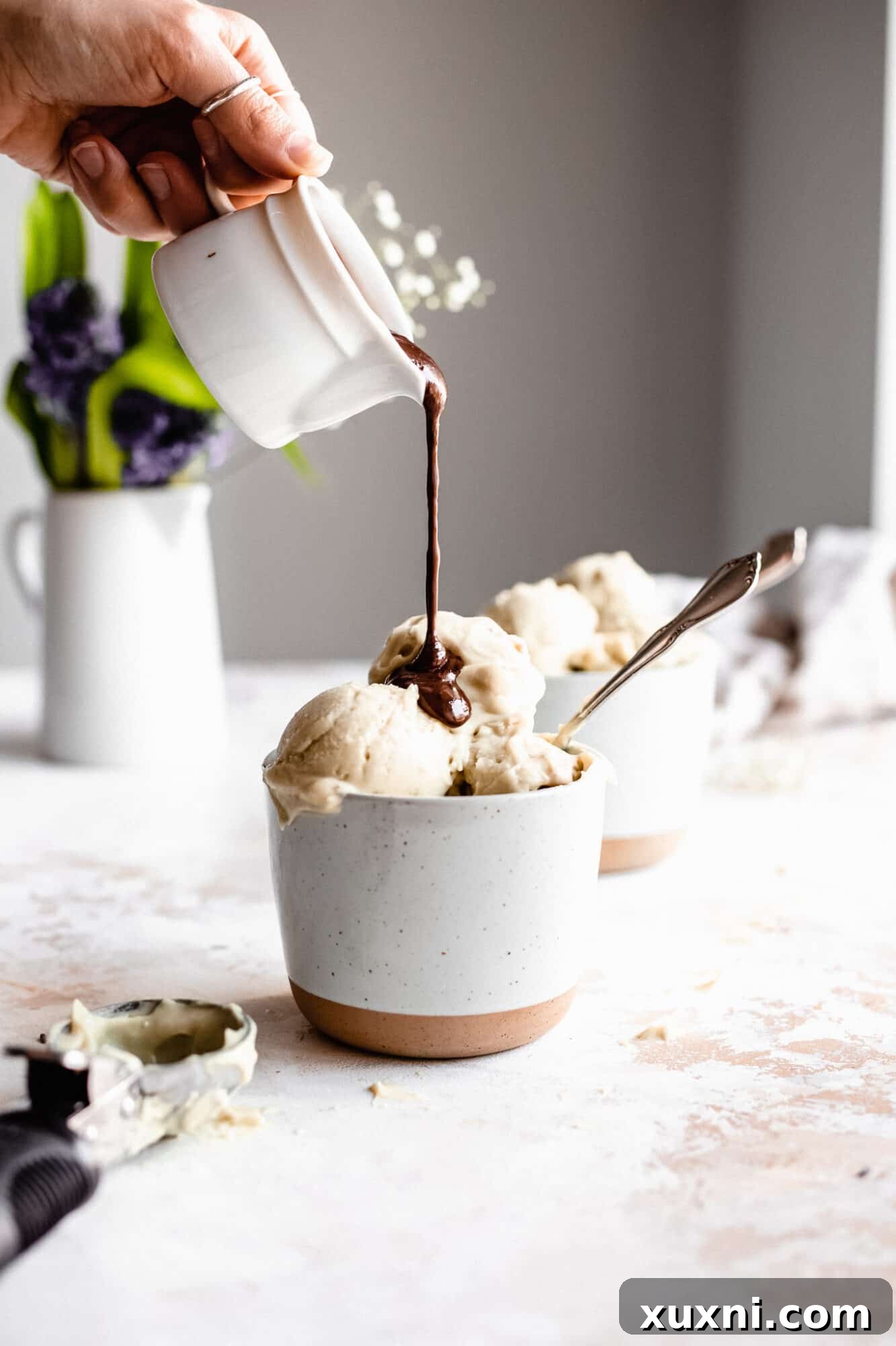 Vegan hot fudge being poured on paleo vanilla ice cream