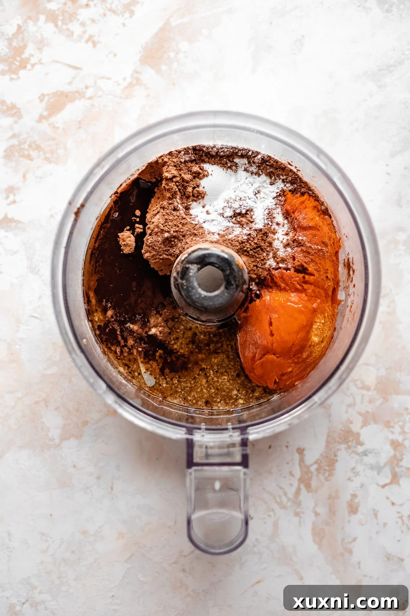 sweet potato brownie ingredients being added to a food processor
