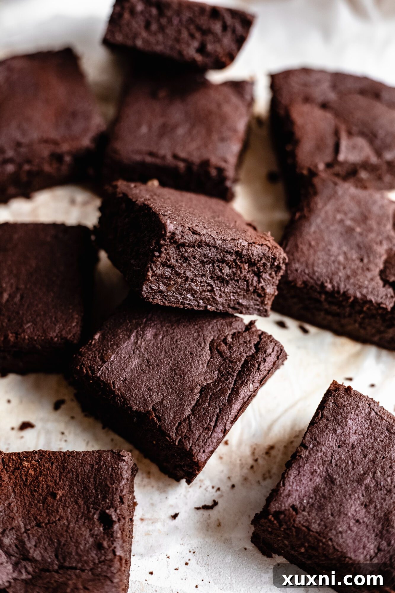 a pile of messy yet tempting vegan brownies on parchment paper