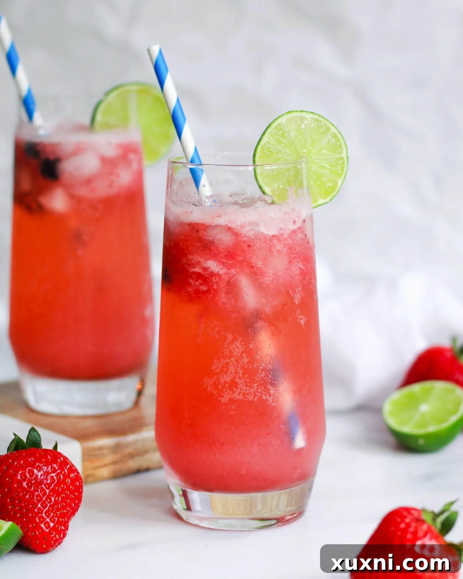 Blushing Berry Mockarita 2 Two vibrant virgin strawberry margaritas garnished with fresh lime slices, perfect for a sunny day.