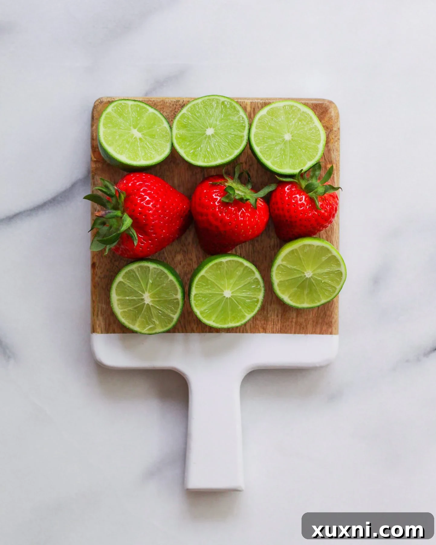 Blushing Berry Mockarita 4 Fresh strawberries and vibrant limes arranged on a rustic cutting board, ready for a healthy mocktail recipe.