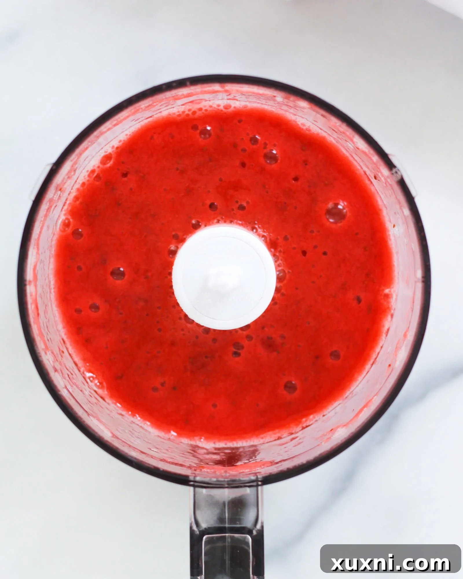 Blushing Berry Mockarita 6 A bowl of vibrant strawberry puree, showcasing the rich color and smooth texture, ready for mocktail preparation.