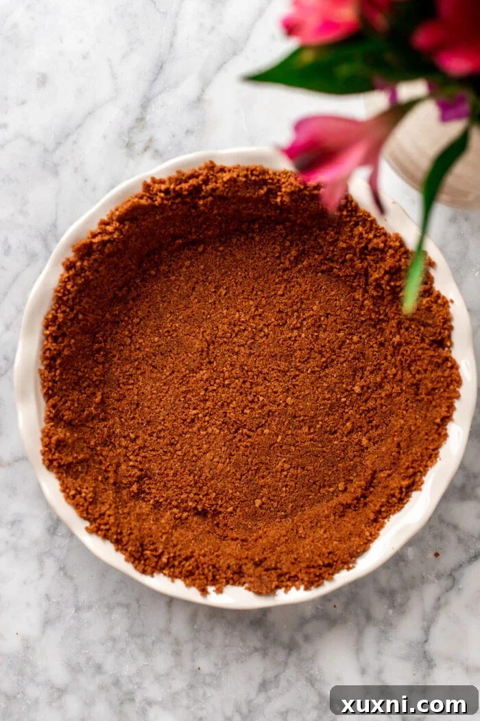 grahama cracker crust being pressed into a pie dish