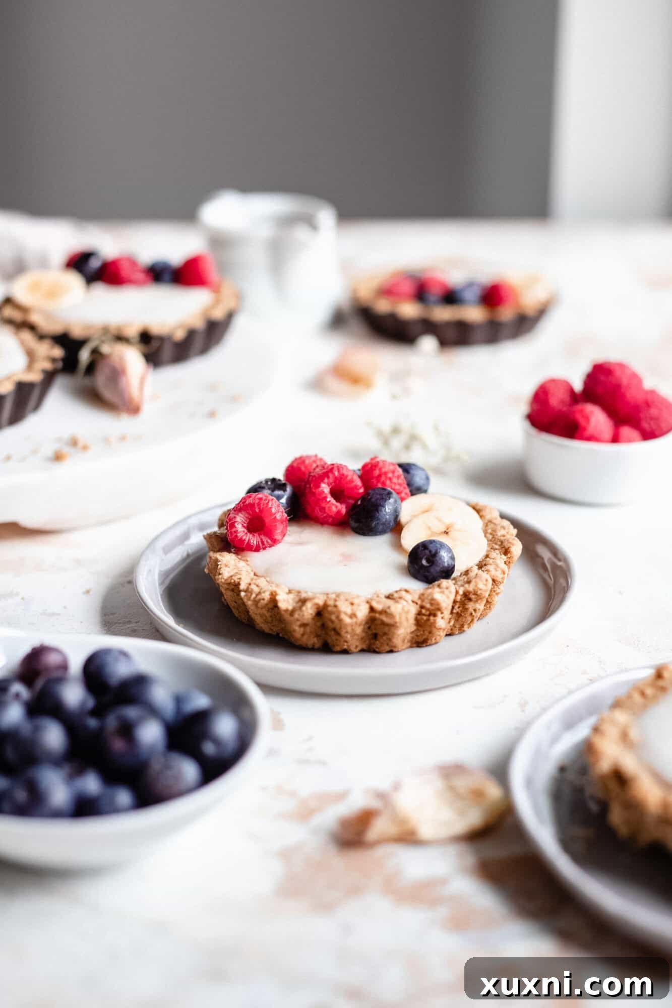 A beautifully presented mini fruit tart on a plate, showcasing its vibrant fresh fruit and creamy custard filling.