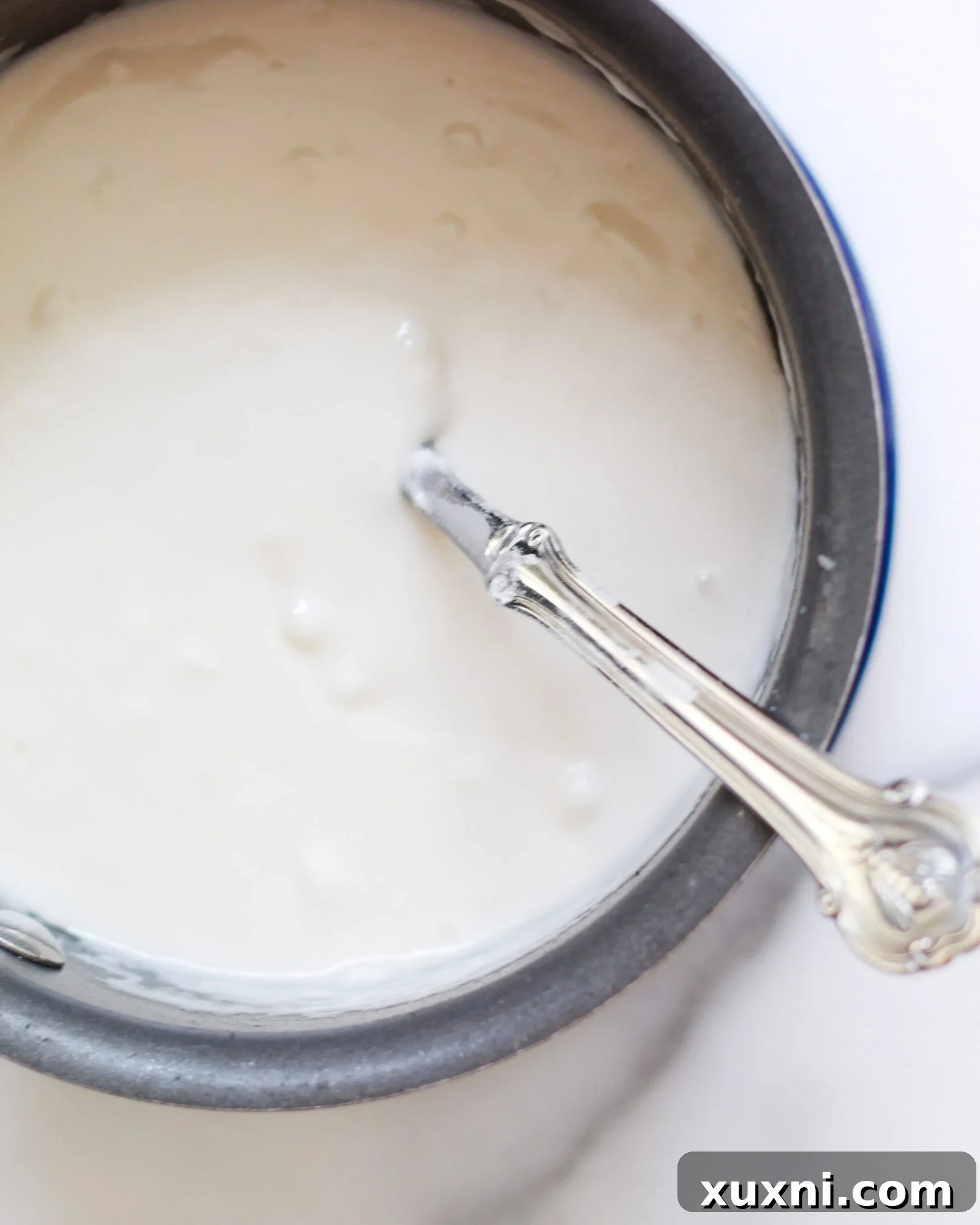 Vegan vanilla custard simmering gently in a saucepan, beginning to thicken.