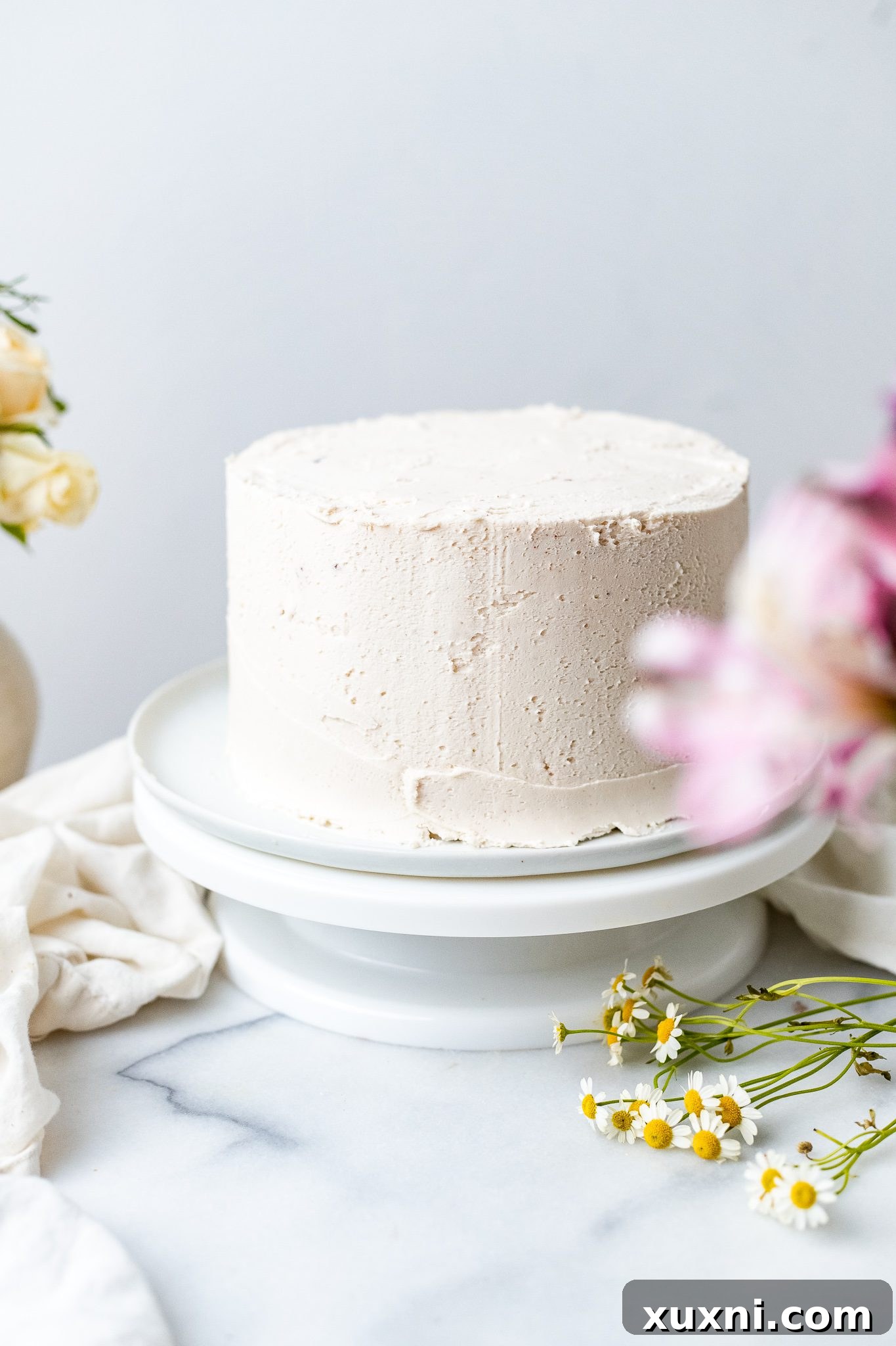 Freshly frosted chocolate coconut cake with smooth cream cheese frosting, awaiting decoration.