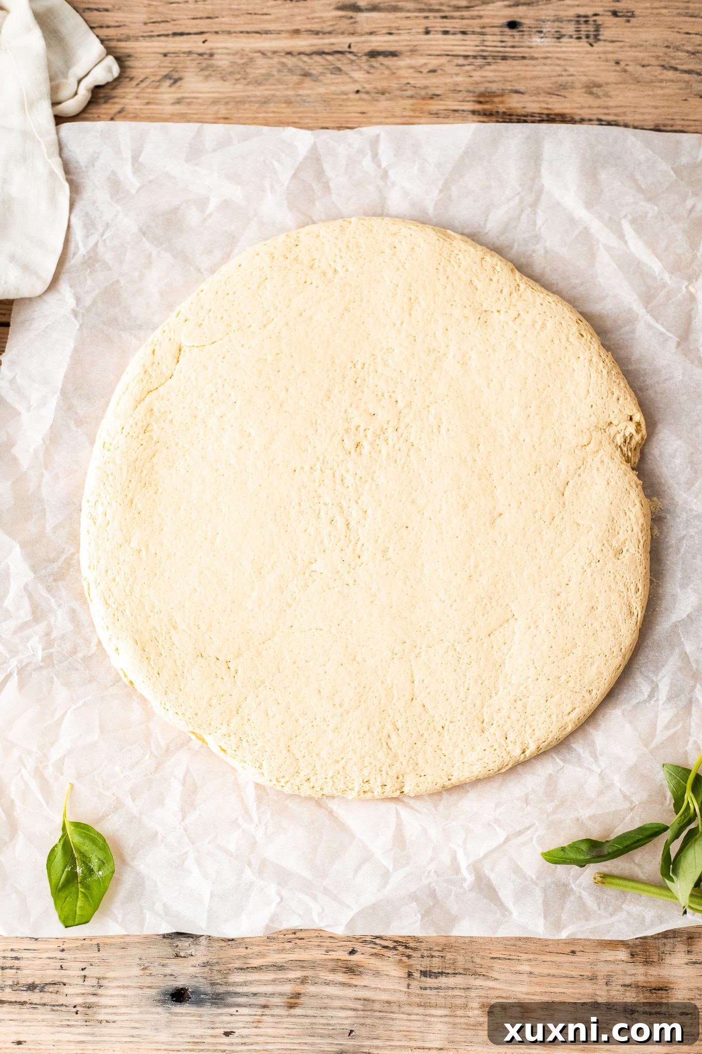 Gluten free pizza dough rolled out on parchment paper