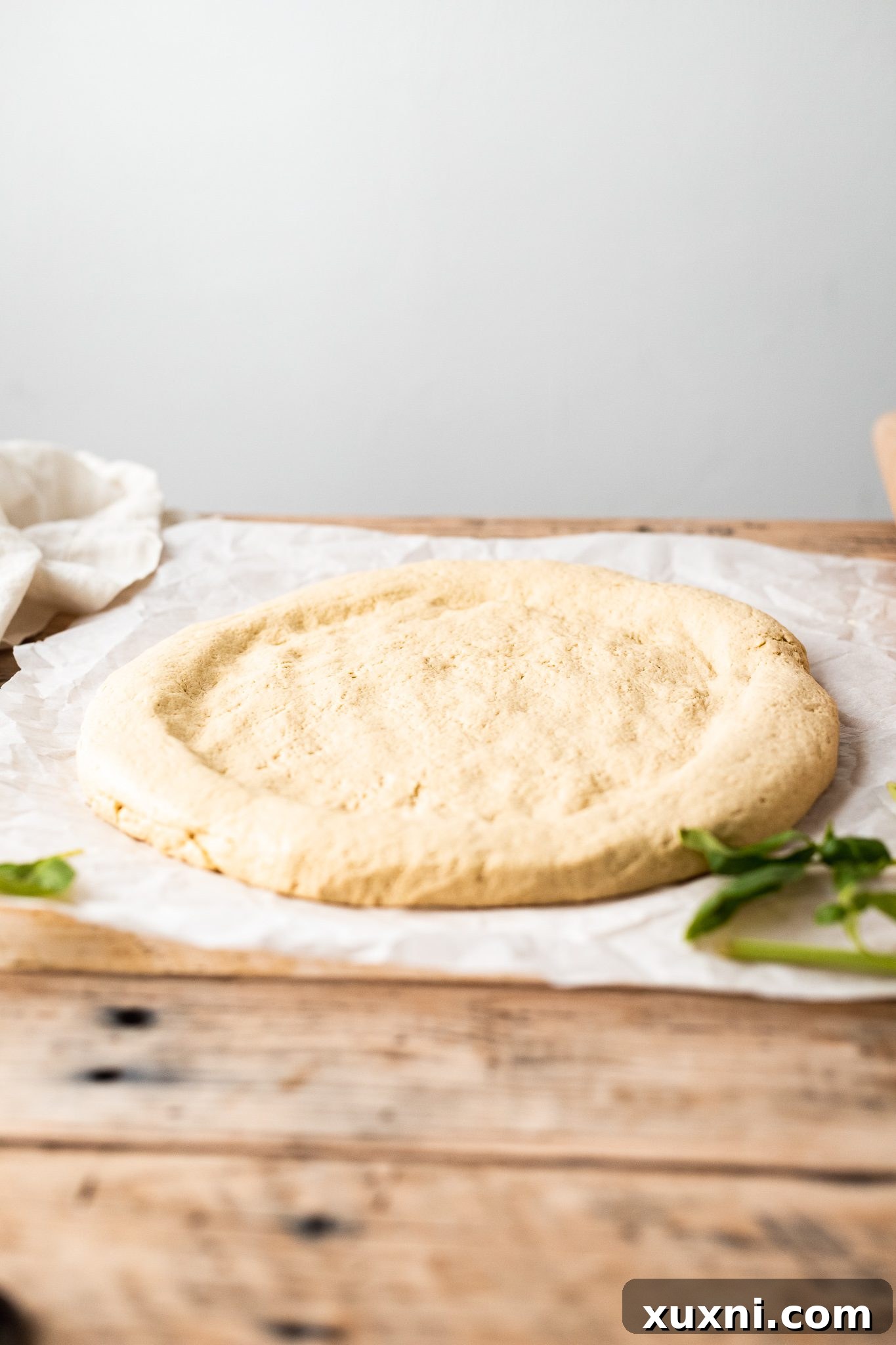 Unbaked gluten free pizza dough on a baking sheet with formed crust