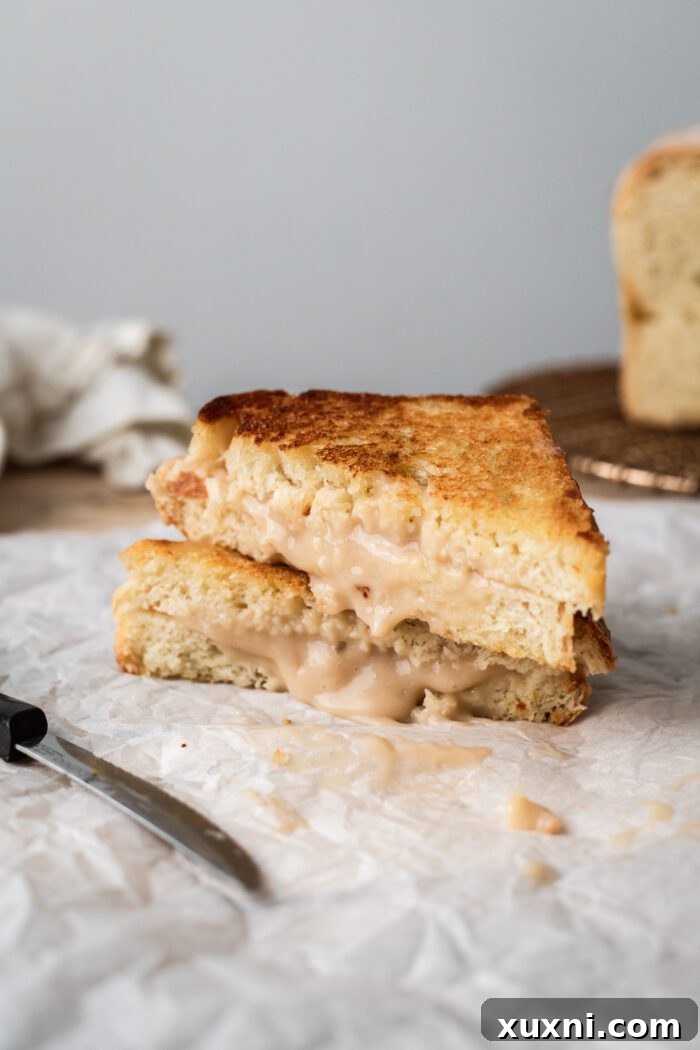 Multiple slices of vegan grilled cheese made with dairy-free mozzarella, stacked artfully on parchment paper