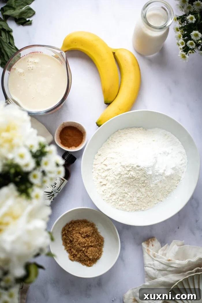 various vegan banana pancake ingredients laid out on a table, including flour, bananas, sugar, and milk