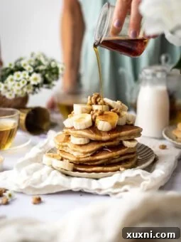 stack of delicious vegan banana pancakes with maple syrup being poured over them