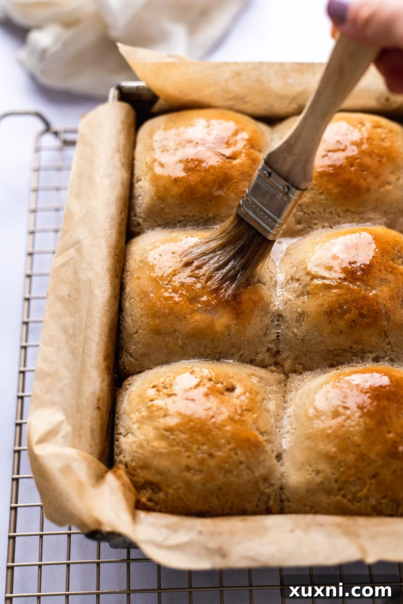 Pillowy Soft Gluten-Free Vegan Dinner Rolls, Made Easy 12 gluten free dinner rolls being brushed with more vegan butter