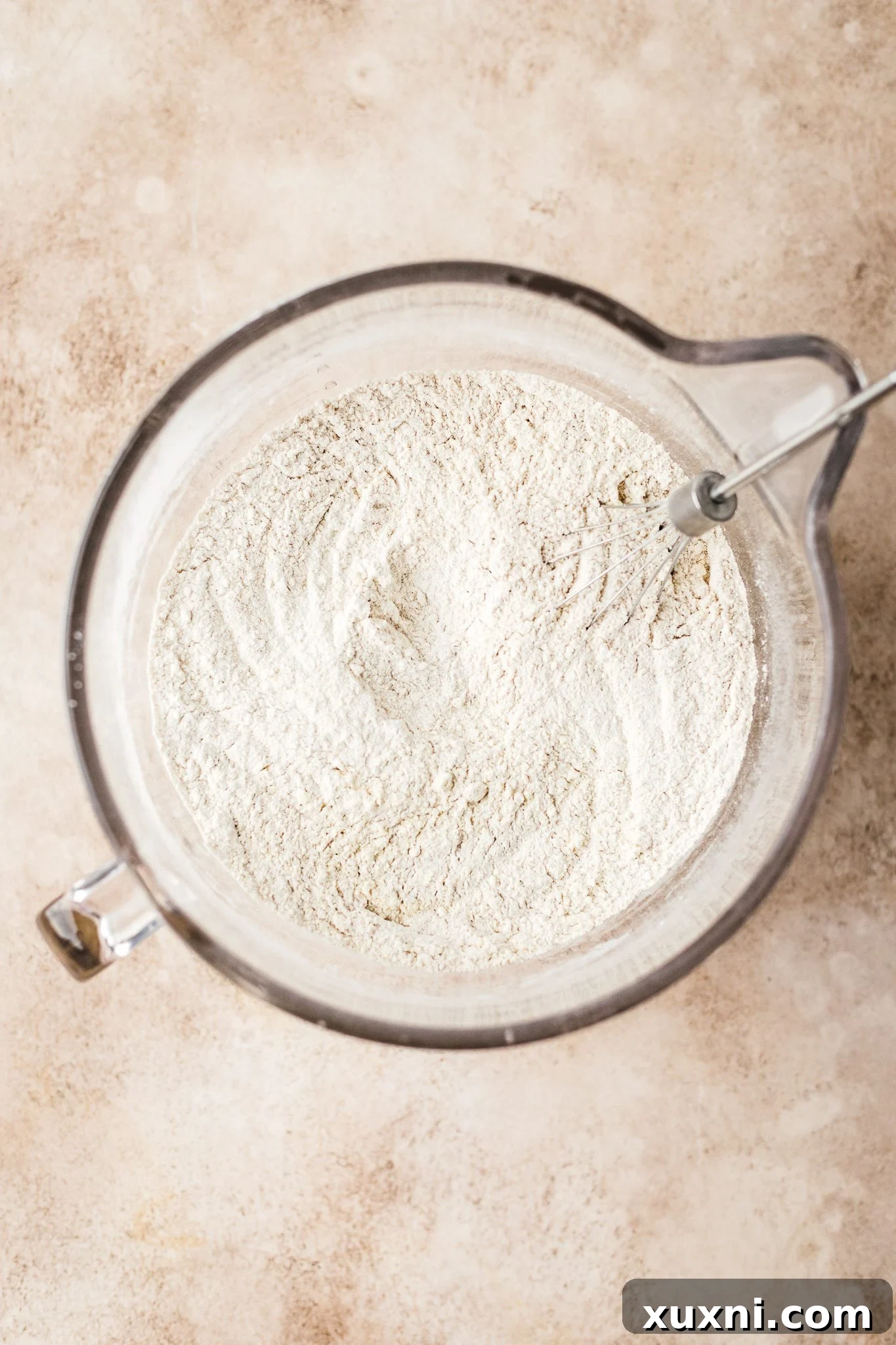 whisking the dry ingredients for burger buns in a bowl