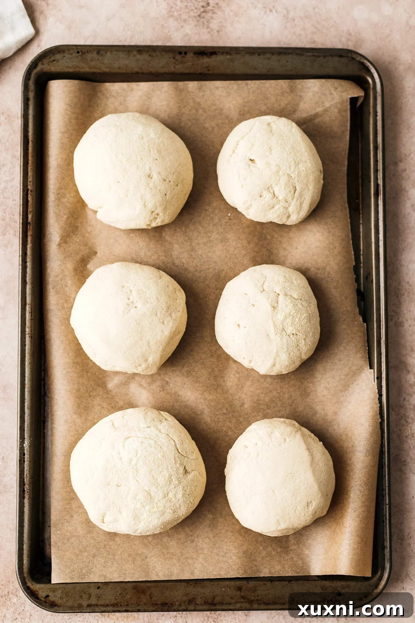 gluten free burger buns placed on parchment paper before rising