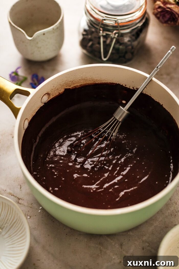 Quick and Easy Vegan Chocolate Pudding Dream 7 Melted vegan chocolate, butter, and vanilla extract being stirred into the cooked pudding in a saucepan.