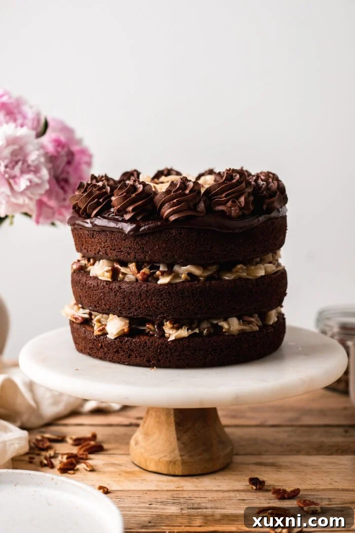 Decadent vegan German chocolate cake on a stylish cake stand, showcasing its rich layers of chocolate and sticky coconut pecan frosting.