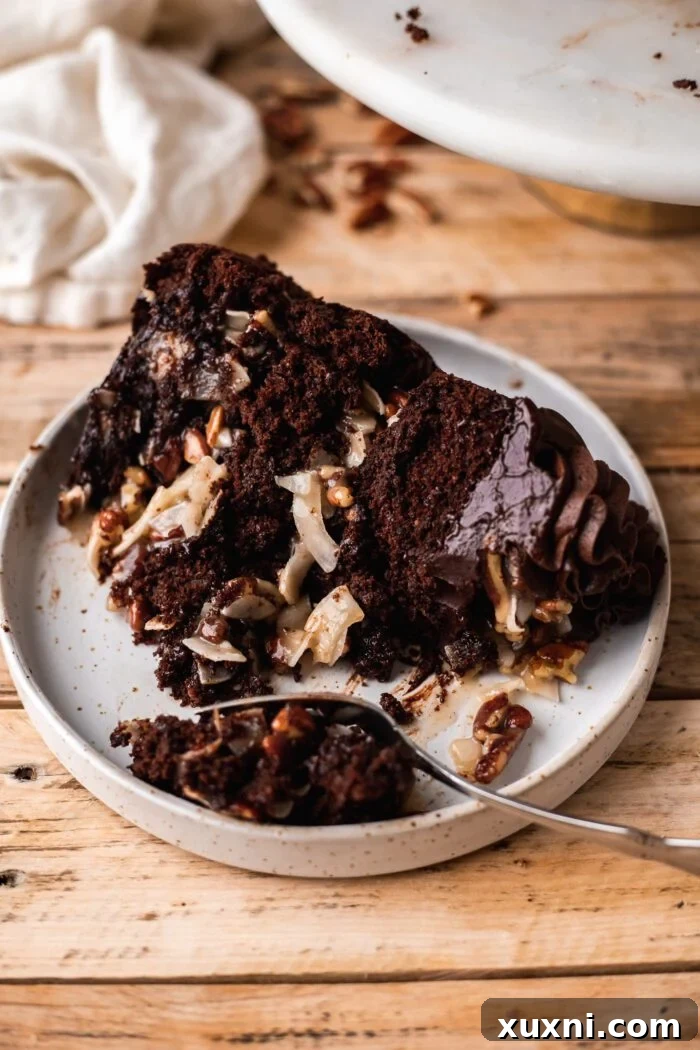 A beautifully plated slice of vegan German chocolate cake, showcasing the luscious layers of chocolate cake, coconut pecan filling, and chocolate ganache.