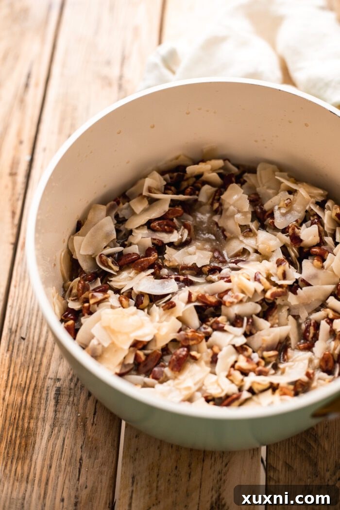 Rich coconut pecan frosting cooking in a saucepan, showing its caramel-like texture.
