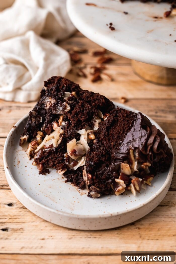 A delicious slice of vegan German chocolate cake on a white plate, ready to be enjoyed.
