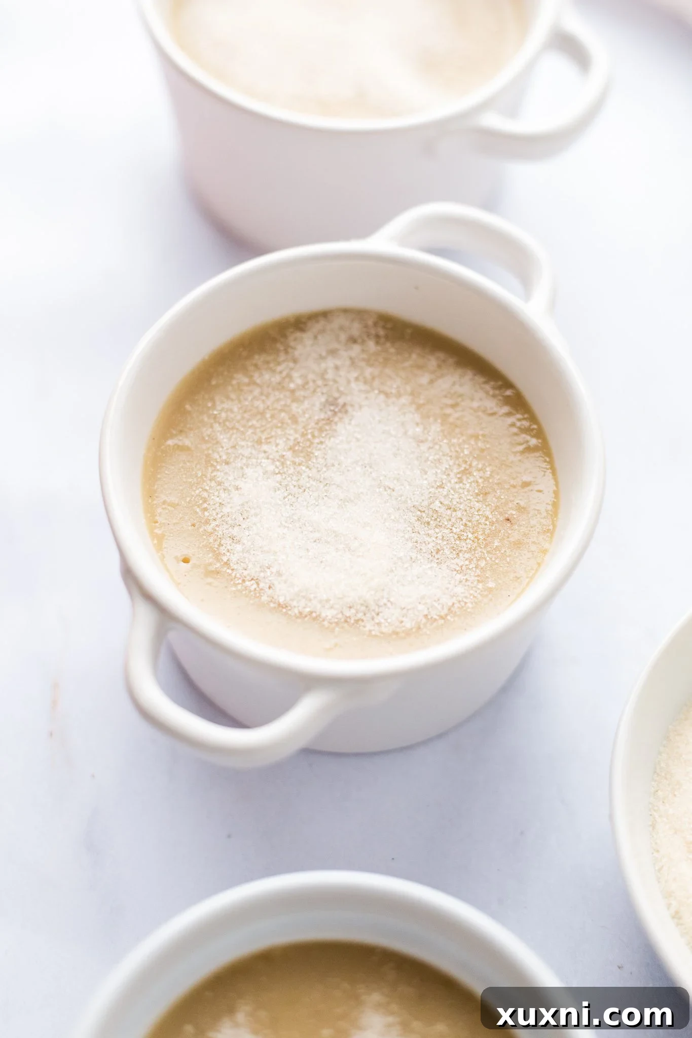 A ramekin of vegan crème brûlée with a layer of sugar sprinkled on top, ready for torching.