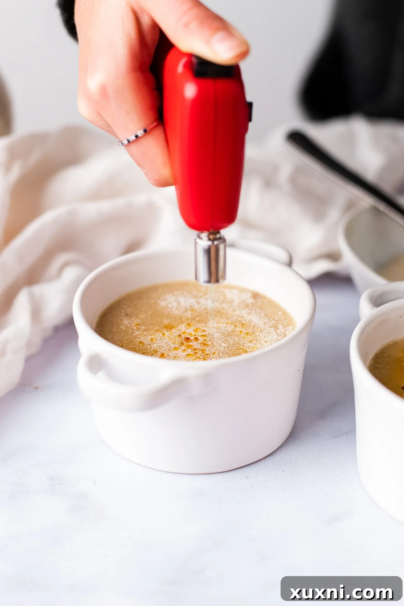 A culinary torch in action, caramelizing the sugar on top of a vegan crème brûlée.