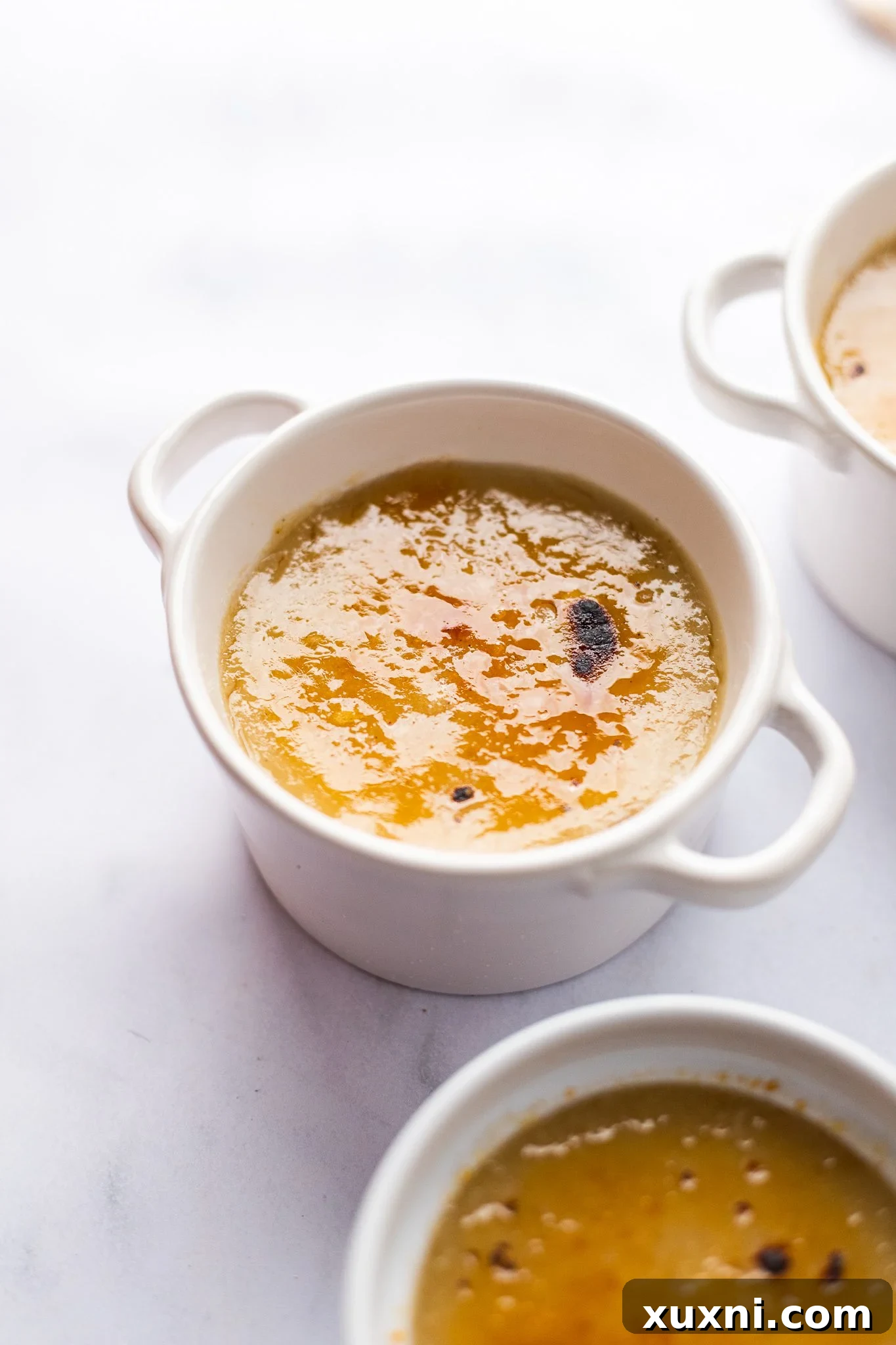 A close-up shot of a finished vegan crème brûlée with a perfectly caramelized top, ready to be cracked.