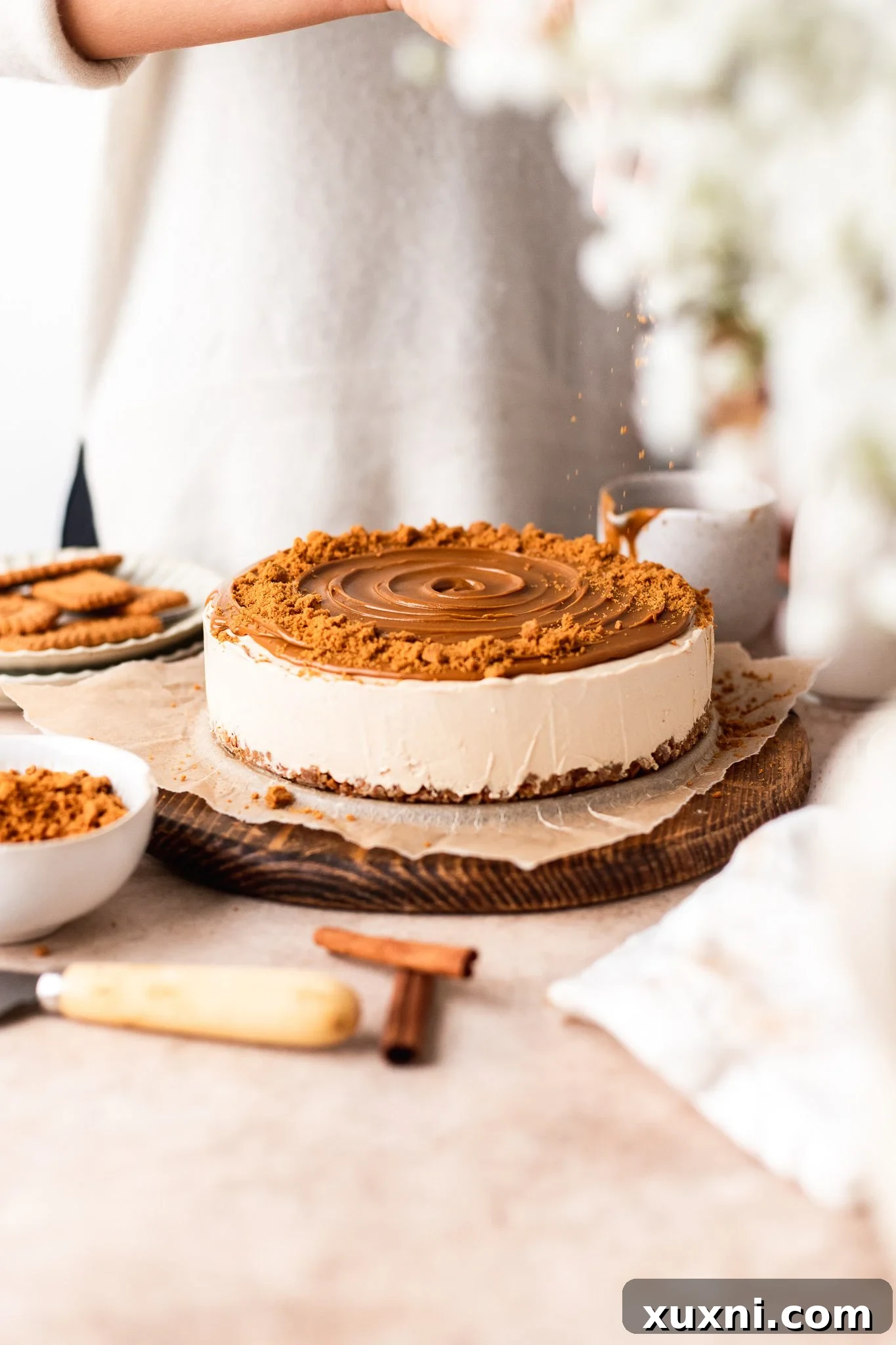 topping the vegan Biscoff cheesecake with crushed cookies