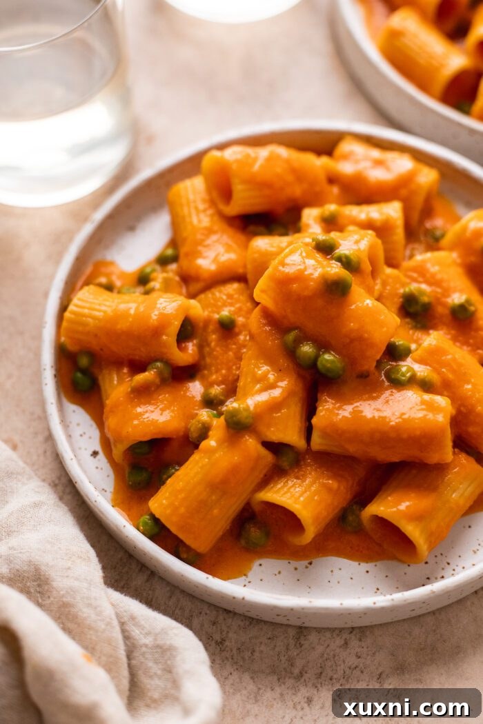 A close-up of a serving of vegan vodka pasta, showing the rich sauce clinging to the pasta, garnished with fresh herbs.
