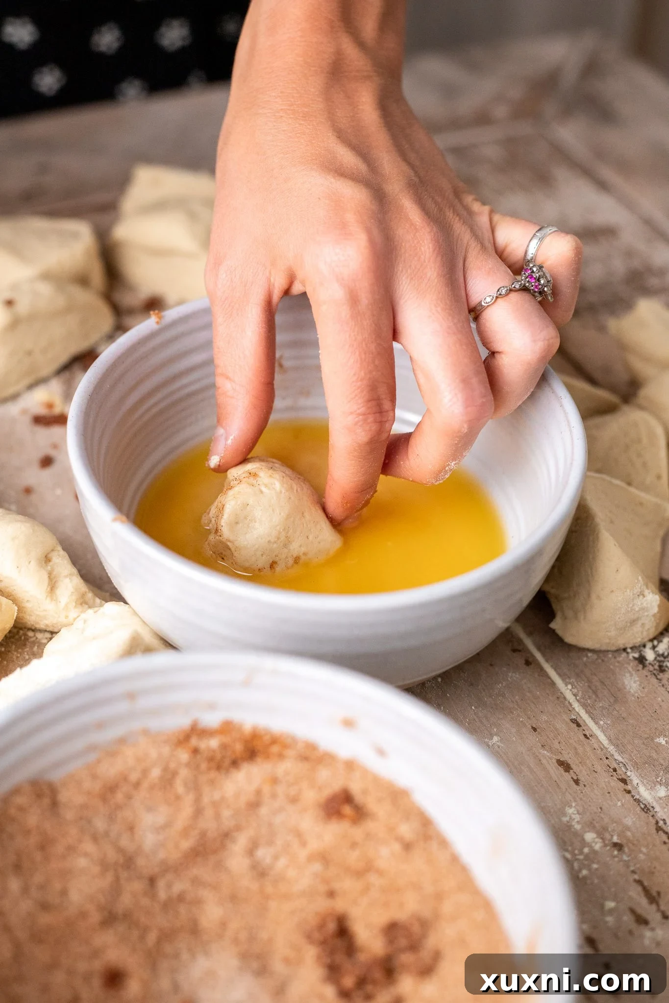 The Classic Soft and Fluffy Gluten-Free Monkey Bread 6 A small dough ball being dipped into a bowl of melted vegan butter, ensuring full coverage before the next step.