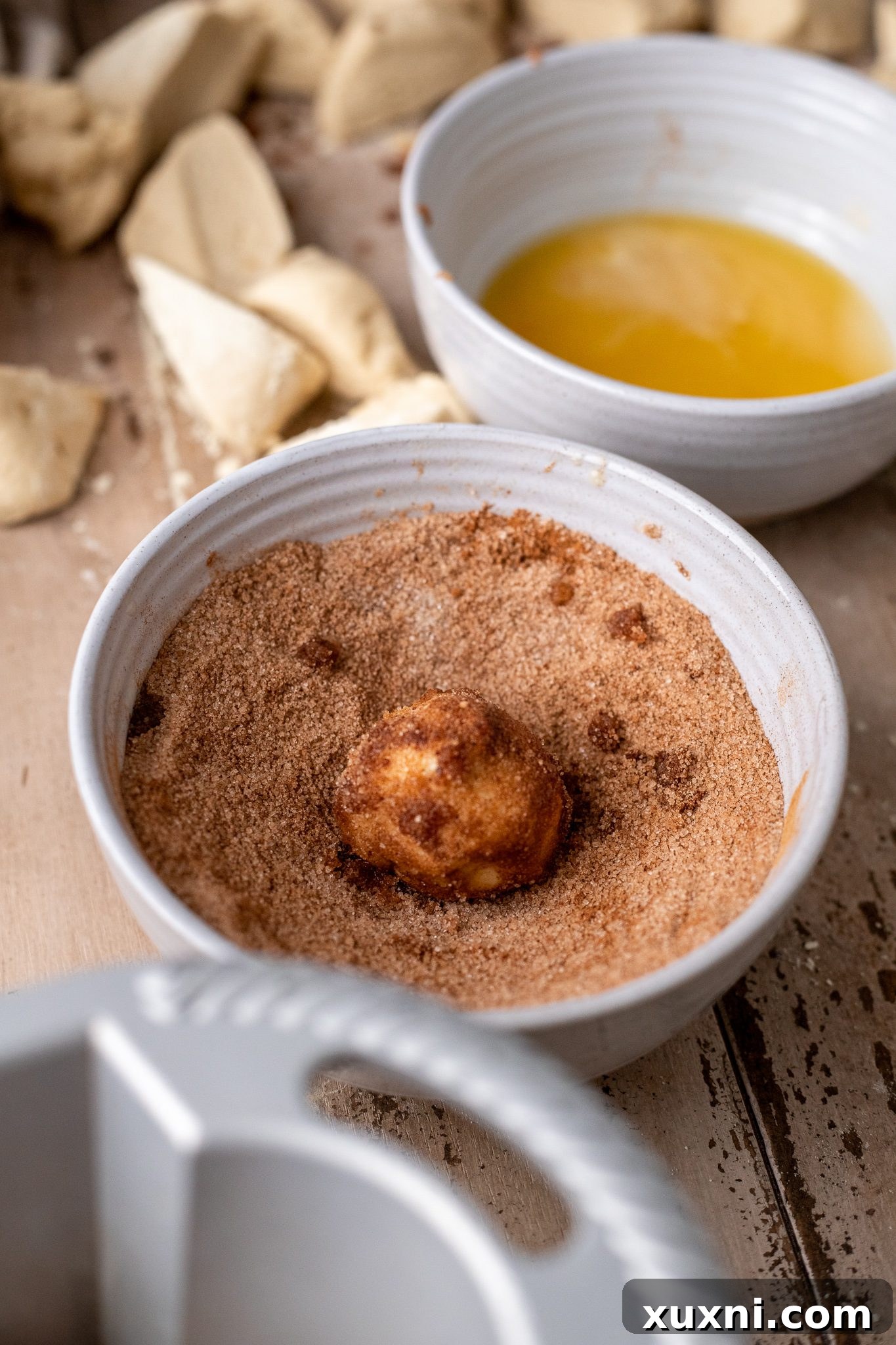 The Classic Soft and Fluffy Gluten-Free Monkey Bread 7 A butter-dipped monkey bread dough ball being rolled in a generous coating of cinnamon sugar, ready for the bundt pan.