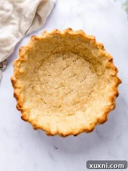 Baked gluten-free pie crust next to a linen cloth.