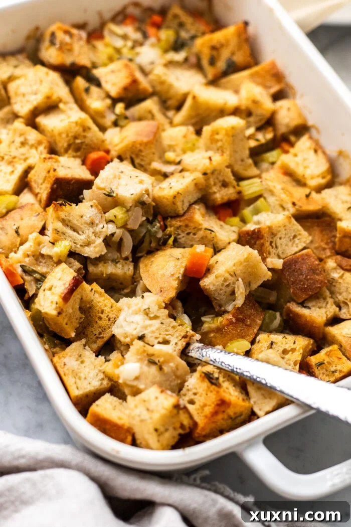 scooping the vegan stuffing, a close-up shot of a spoon scooping a portion of the golden-brown herbed stuffing from a casserole dish