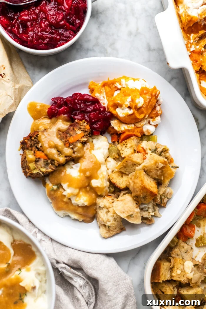 plate of vegan stuffing with thanksgiving food, a Thanksgiving plate featuring a generous portion of herbed vegan stuffing alongside other holiday dishes