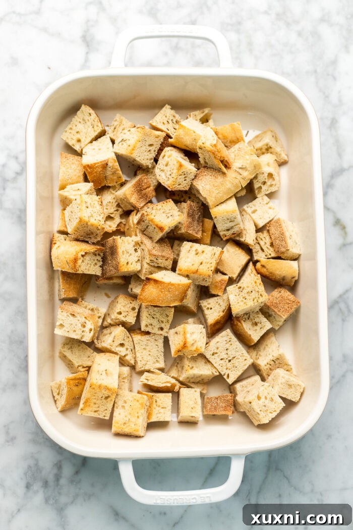 sourdough before baking, cubed bread pieces laid out in a casserole dish, prior to mixing with other ingredients