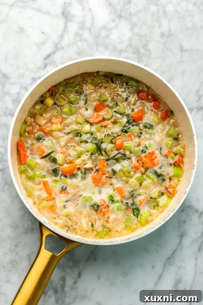 veggies cooking in broth, a skillet with sautéing celery, carrots, and onions, along with fresh herbs