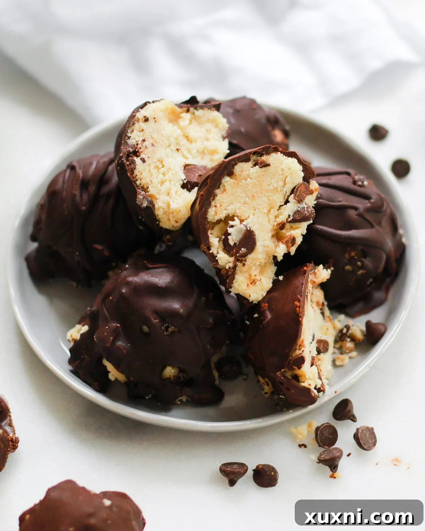 bowl of chocolate chip cookie dough truffles, one split open to reveal the cookie dough