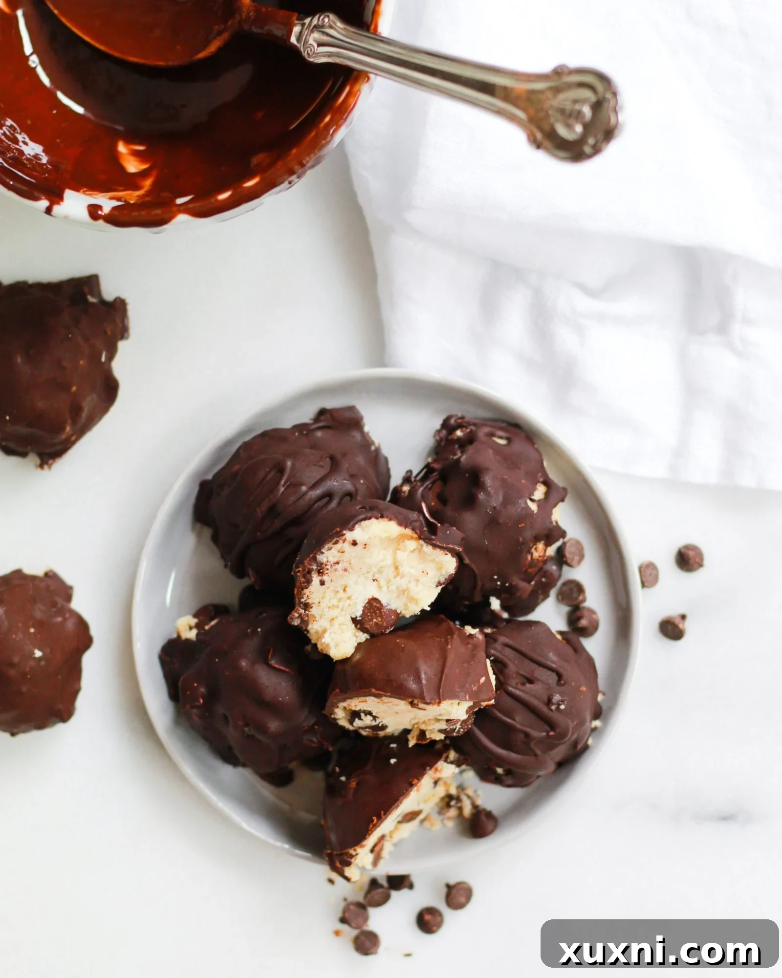 plate of vegan cookie dough truffles with bowl of melted chocolate