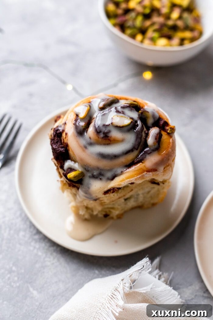 Vegan Chocolate Pistachio Sweet Roll on a plate, garnished with chopped pistachios and a light glaze