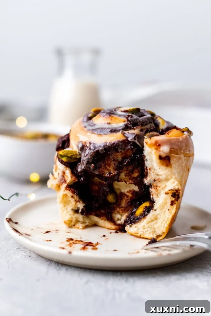 A single Vegan Chocolate Pistachio Sweet Roll on a white plate with a fork, ready to be enjoyed