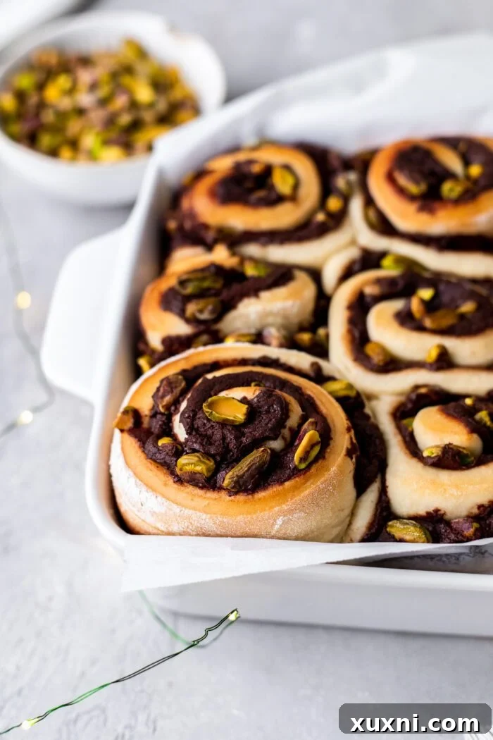 A close-up of baked vegan chocolate pistachio swirls, perfectly golden brown with visible layers of chocolate and pistachios