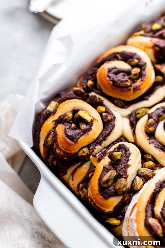 Close-up of three freshly baked Vegan Chocolate Pistachio Sweet Rolls, showing their fluffy texture and delicious filling.