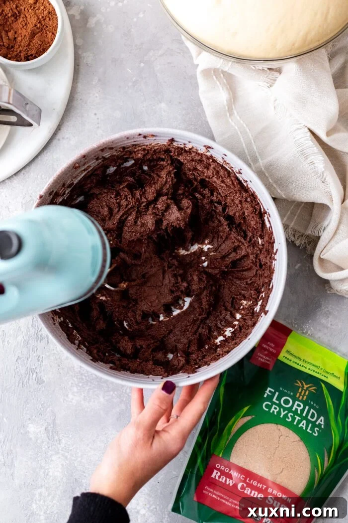 Ingredients for chocolate cream cheese filling being mixed in a bowl with a hand mixer