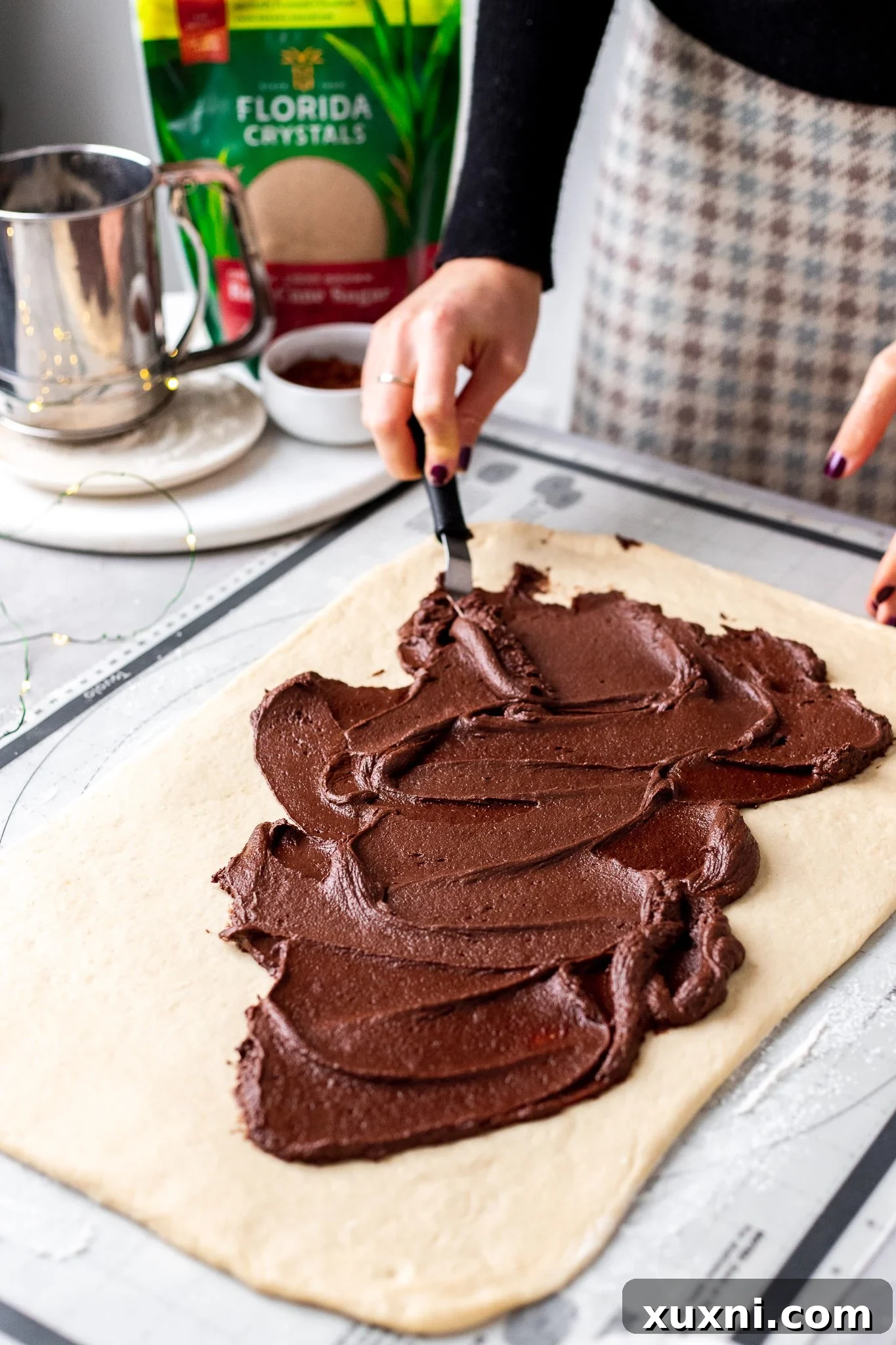 Spreading chocolate cream cheese filling on rolled-out dough