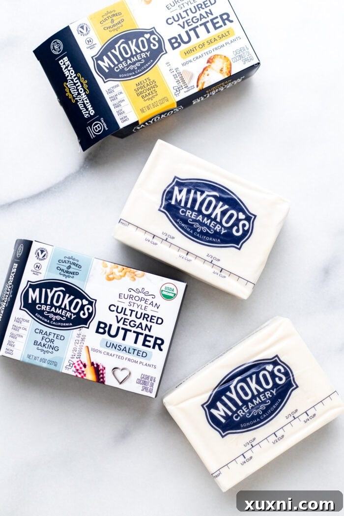 Various brands of block vegan butter, ideal for baking, displayed on a counter.
