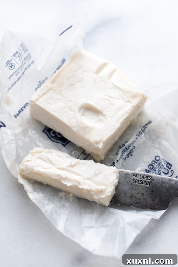 Neatly sliced pats of vegan butter in a microwave-safe bowl, ready for quick softening.