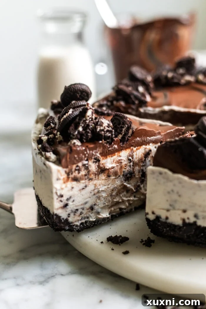 A whole vegan Oreo cheesecake, beautifully sliced and presented on a cutting board, topped with chocolate ganache and additional Oreos.