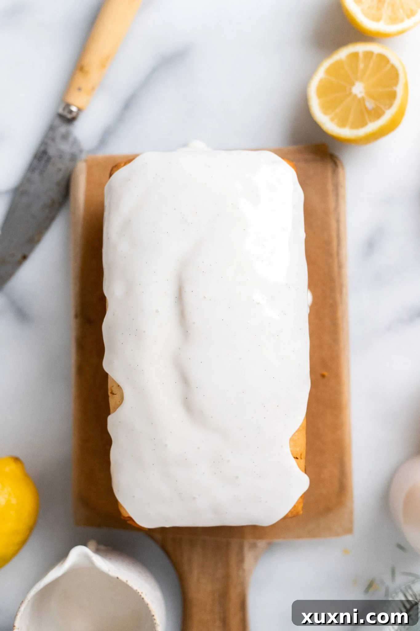 Glazed vegan lemon pound cake on a cooling rack, showing the set vanilla glaze.