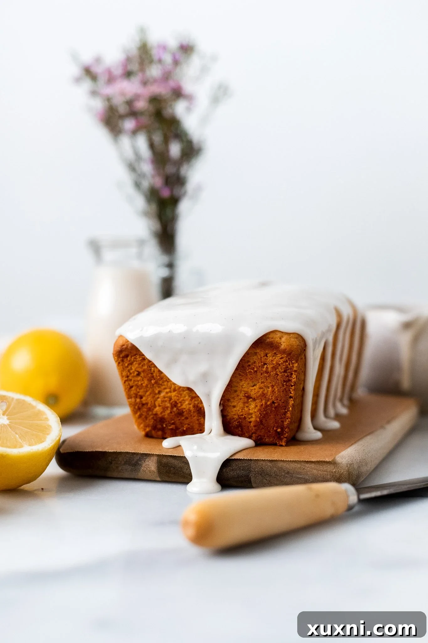 Close-up of vanilla bean glaze dripping down the sides of a vegan lemon pound cake.