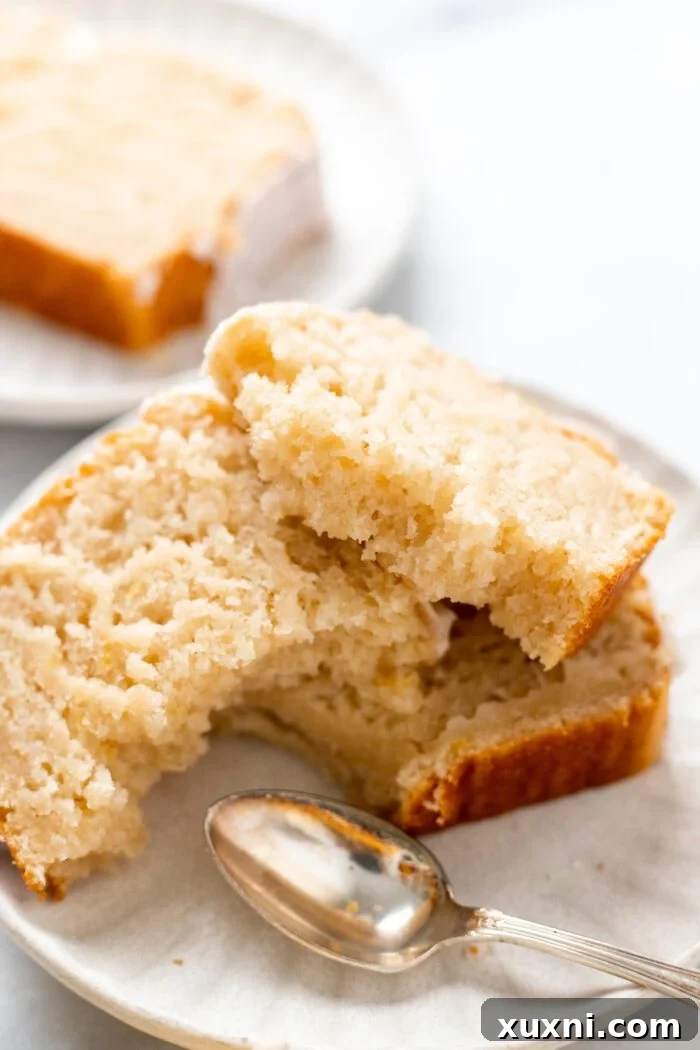 Close-up of a broken slice of vegan lemon pound cake, highlighting its soft, airy crumb.