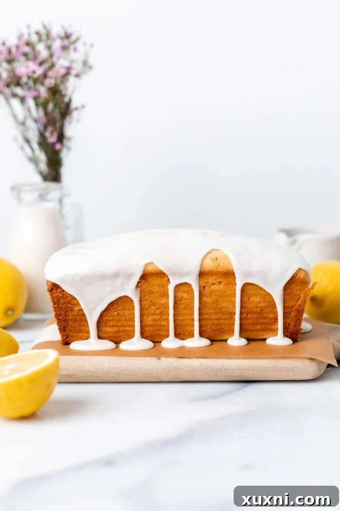 Whole Vegan Lemon Pound Cake adorned with a generous drizzle of vanilla bean glaze, ready to be sliced.